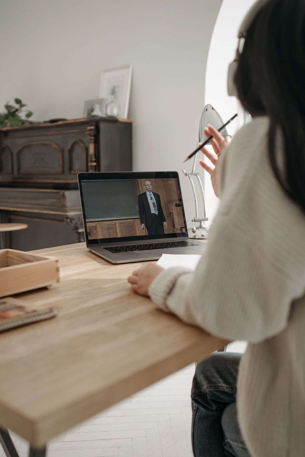 A person taking an online class on a laptop, wearing headphones